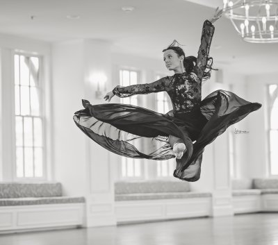black and white image of a ballet dancer doing a split leap in a black flowing skirt
