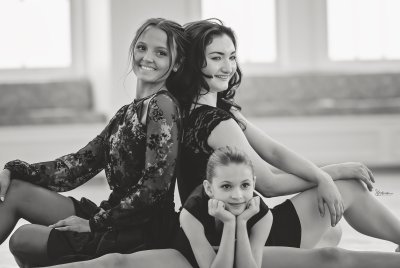 three dancers posing together on the floor in black and white